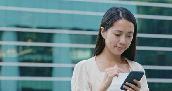 Woman look at mobile phone with business tower background