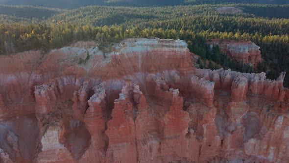 amazing colorful sandstone strata cliffs bordering a lush pine forest in Utah. Aerial panning