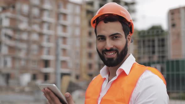 Portrait of Construction Worker on Building Site with Tablet Looking at the Camera