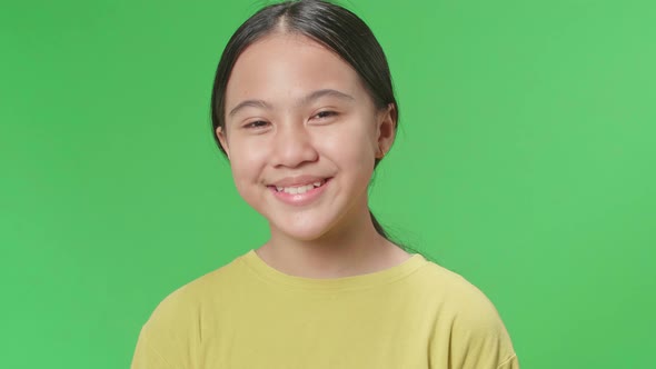 Young Asian Kid Girl Warmly Smiling On Green Screen Background In The Studio