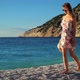 Young woman in dress walking on a beach at sunset over the sea. - VideoHive Item for Sale
