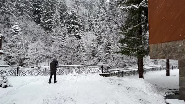 Photographer  A Tourist Takes Pictures of a Snowcovered Pine Forest and Mountains