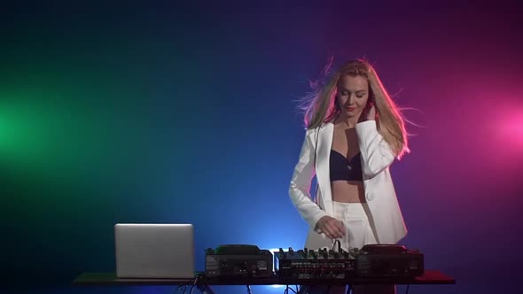 Beautiful, Sexy Dj Girl in White Jacket, Headphones Playing Music and Dancing, Hand in the Pocket