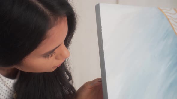 Latina Artist Holding Brush Painting Canvas Sides. - Close Up Shot