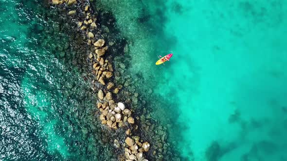 Overhead view of a couple in a Kayak in the waters of Mambo Beach with a breakwater on the side, Cur