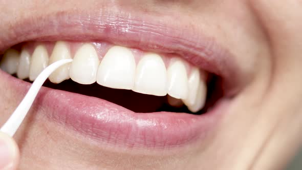 close up woman mouth, clean and floss space between teeth with plastic toothpick. smiling girl with 