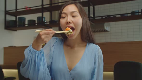 Lovely Asian Woman Eating Delicious Sushi Roll at Cafe