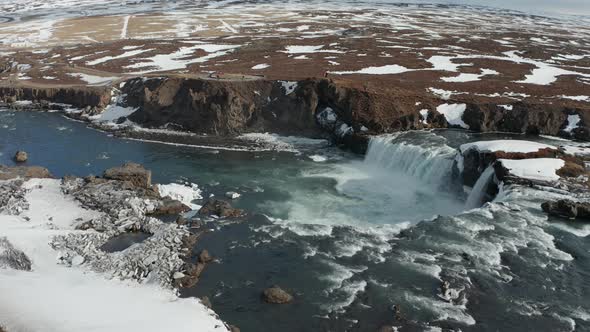 Aerial View of Godafoss Waterfall with Snowy Shore and Ice. Iceland. Winter 2019