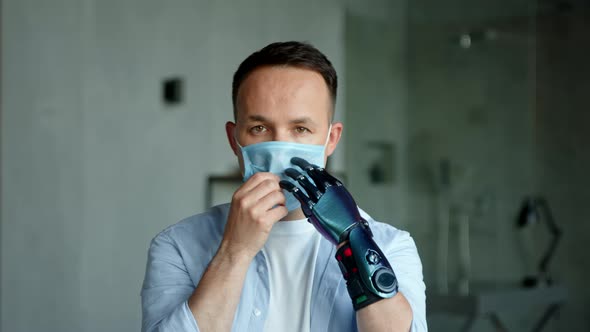 Serious man with artificial high tech hand prothesis looks straight