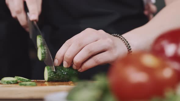 Hands of a Woman Chopping Vegetables on a Wooden Board