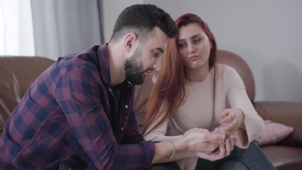 Angry Redhead Caucasian Woman Putting Wedding Ring Into Man's Hand and Turning Away, Stressed