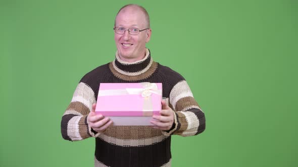 Happy Mature Bald Man Smiling While Giving Gift Box
