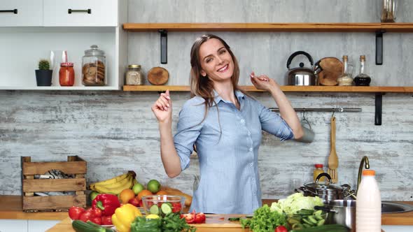 Joyful Modern Housewife Dancing at Kitchen Preparing Healthy Food