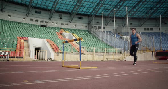 Young Runner Jumping Over Hurdle