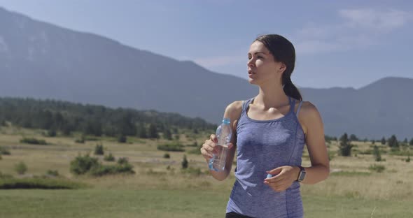 Slow Motion Shot of Sporty Trail Running Woman While Drinking Water and Resting From Intense Jogging