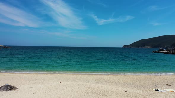 Empty sandy beach with crystal clear turquoise blue water by the Mediterranean coast in Greece.