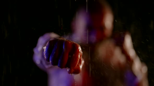 Closeup of a Male Fist in Streams of Water in the Dark