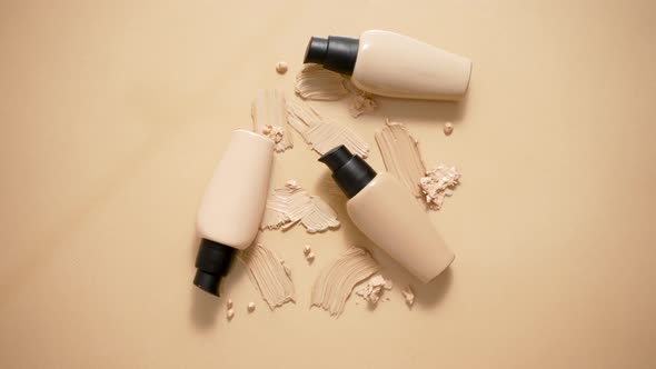 Bottles of Makeup Foundation and Samples on Beige Background