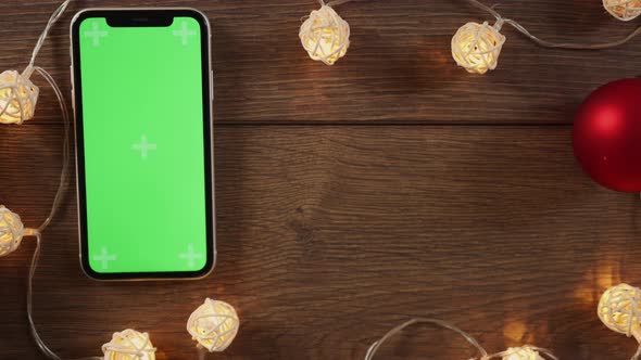 Winter Holidays Present Box and Smartphone Green Screen on Wooden Desk Garland