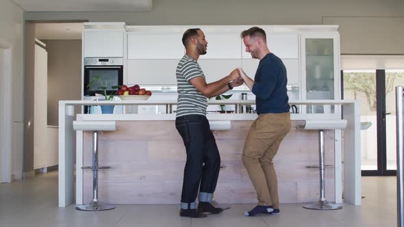 Multi ethnic gay male couple dancing in kitchen