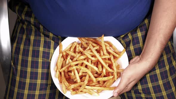 a Fat Man Eating French Fries While Sited