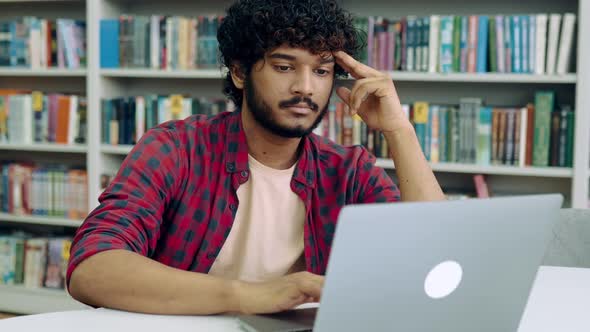 Bored Overworked Sad Arabian or Indian Male Student Stylishly Dressed Sit at Table with Laptop in