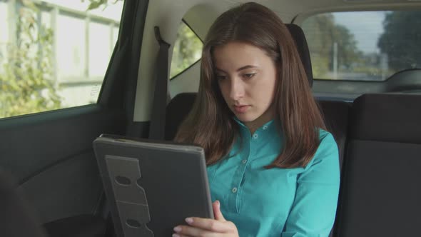 Charming Woman Browsing Online on Tablet Pc in Car