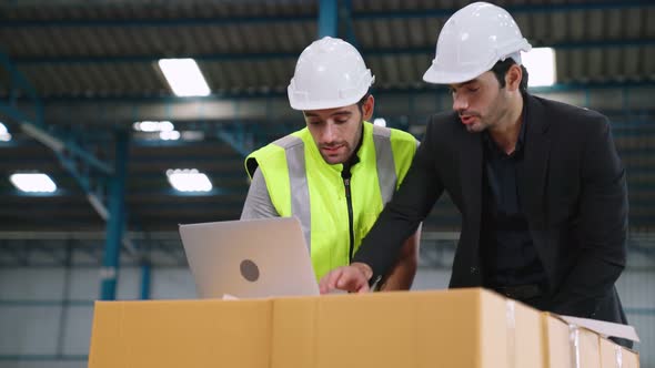 Two Factory Workers Working and Discussing Manufacturing Plan in the Factory