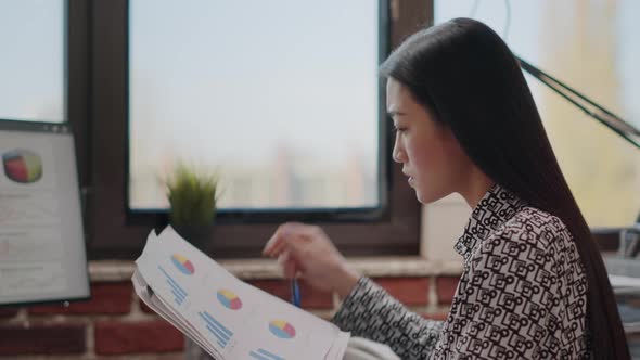 Close Up of Woman Comparing Charts on Papers and Computer