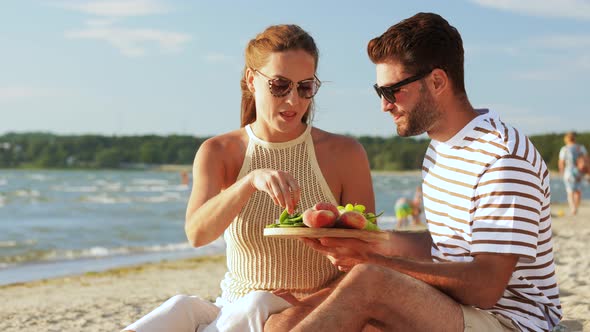 Happy Couple with Food Having Picnic on Beach