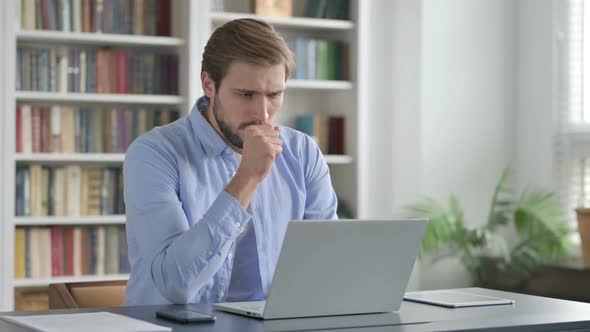 Man Coughing While Using Laptop in Office