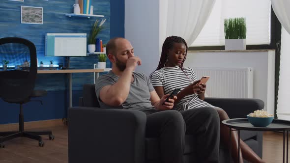 Interracial People Using Smartphones While Sitting Together