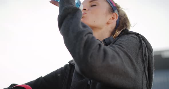 Tilt up video shows of sporty woman drinking water   