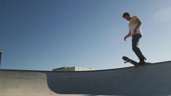 Caucasian man riding and jumping on skateboard on sunny day