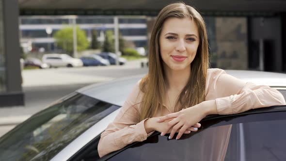 Beautiful Young Woman Standing Near Auto and Posing for Camera. Buying a Car