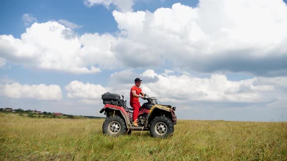 Man in a Black Cap and Red T-shirt on a Colored ATV Rides