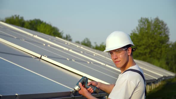 Worker in a Uniform and Hardhat Installing Photovoltaic Panels on a Solar Farm alt