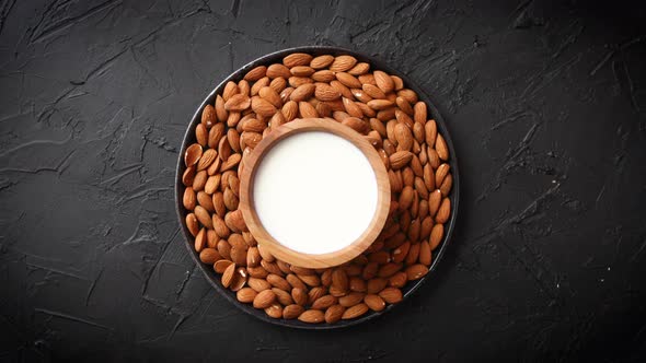 Composition of Almonds Seeds and Milk, Placed on Black Stone Background.