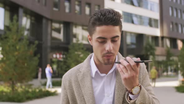  Businessman Talking on Speakerphone on Mobile Phone Outside