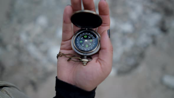 Close View of Metal Compass Spinning in Hand of Young Woman in Nature