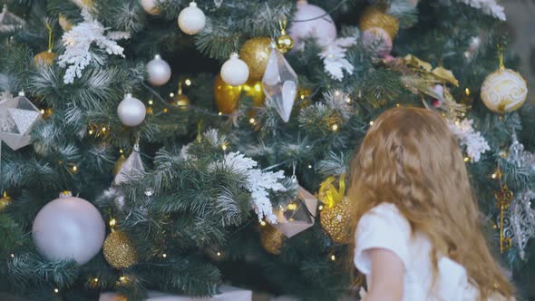 Girl Tries To Get Gift From Under Christmas Tree in Room