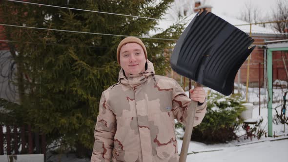 Portrait of a Cheerful Guy Who Has Finished Cleaning the Snow in the Yard and Shows a Thumbs Up