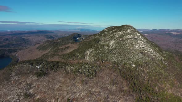 Aerial orbit of a far off snow dusted mountain in Maine