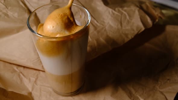 Beautiful composition - hot coffe latte cappucino in a transparent glass. Mixing by spoon