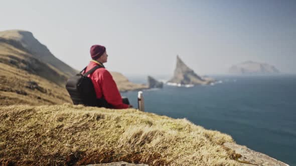 Man Drinking From Water Bottle Cup and Faroe Island Ocean Waters in Background