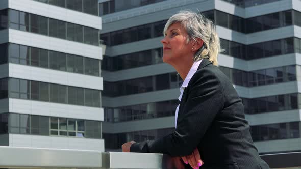 Business Middle Age Woman Looks Around - Company Building in the Background - Closeup