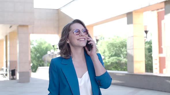 A Woman in a Business Suit Smiles While Talking on the Phone