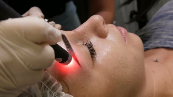 Beautiful Girl Models are Checked for Pigmentation on the Eyebrows Using Special Cosmetology Laser