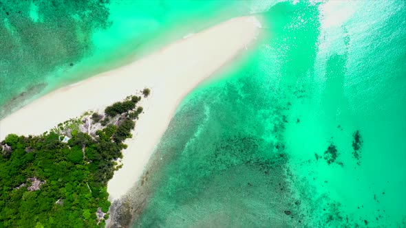 fly over of a white beach jutting into gorgeous turquoise green water in Madagascar