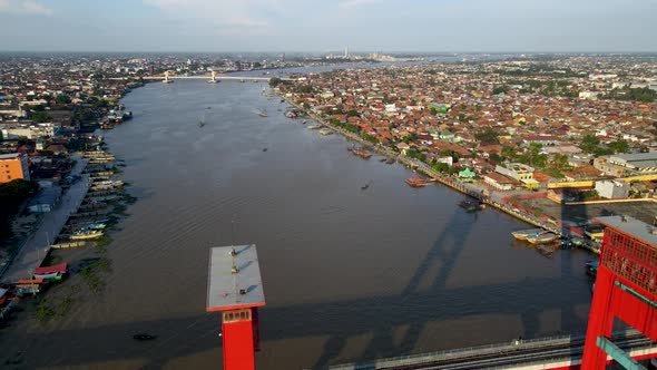 Cityscape of Palembang on sunny day with red color bridge of Ampera, aerial view